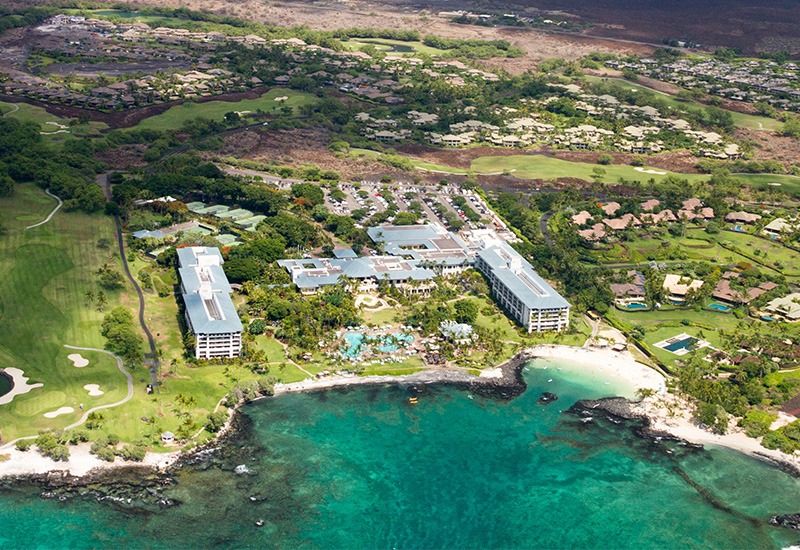 Luftaufnahme des Luxushotels Fairmont Orchid an der Westküste von Big Island, Hawaii, USA, mit Blick auf den wolkenverhangenen Mauna Kea.